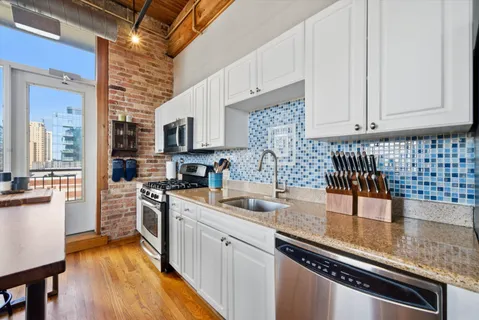 a kitchen with stainless steel appliances granite countertop a sink a stove and cabinets