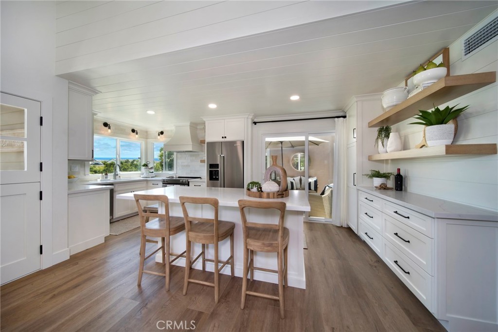 a kitchen with stainless steel appliances kitchen island wooden floors and white cabinets