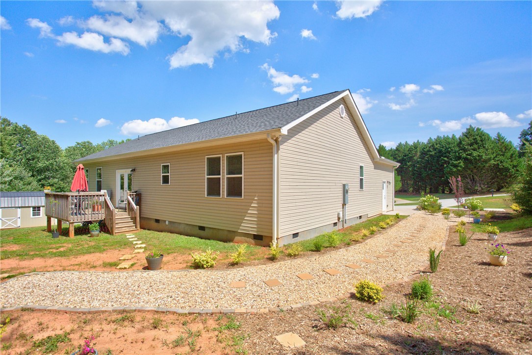 405 Pawnee Drive Walhalla, SC 29691 - Photo 24 of 36 A well-maintained side yard features a gravel path leading to a raised wooden deck.
