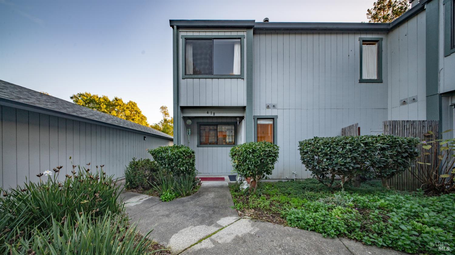 a view of a house with potted plants and a large tree
