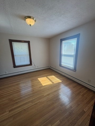 5 Oakland Street Boston, MA 02119 - Photo 13 of 21 an empty room with wooden floor and windows