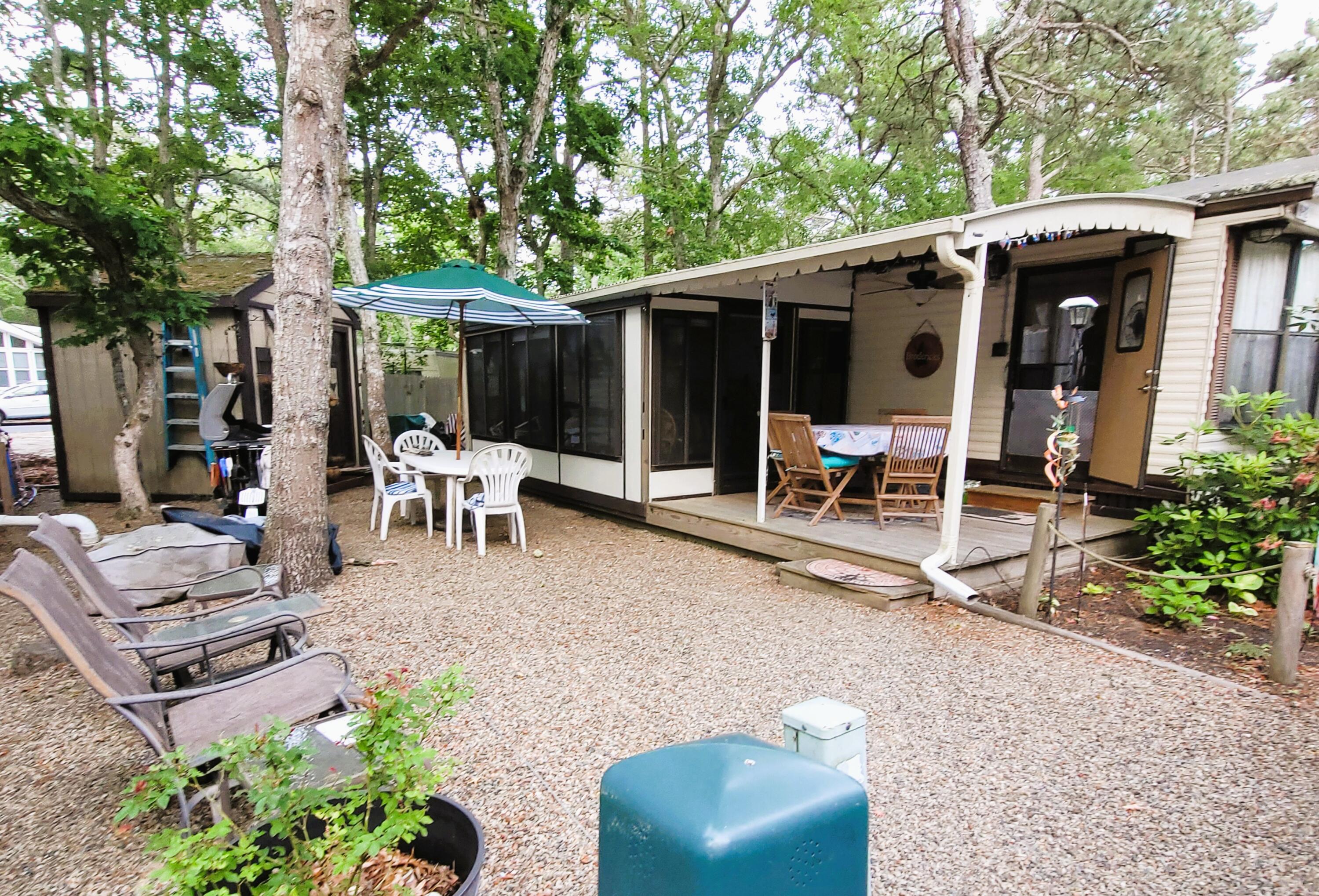 a view of a patio with table and chairs potted plants and large tree