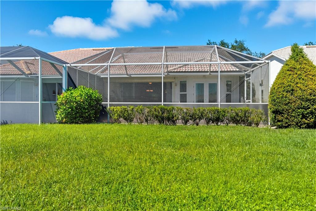 2266 Stacil Circle, Unit 3 Naples, FL 34109 - Photo 40 of 49 Rear view of property featuring a sunroom, a lanai, and a lawn