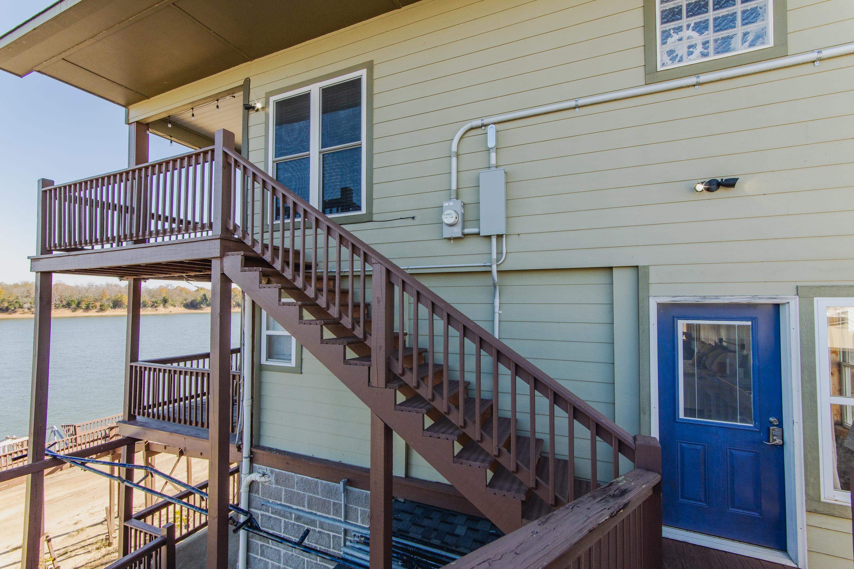 1111 Leaning Trees Lane Adamsville, TN 38310 - Photo 34 of 36 Exterior staircase providing access to an upper-level balcony and a lower-level covered patio, both with water scenery