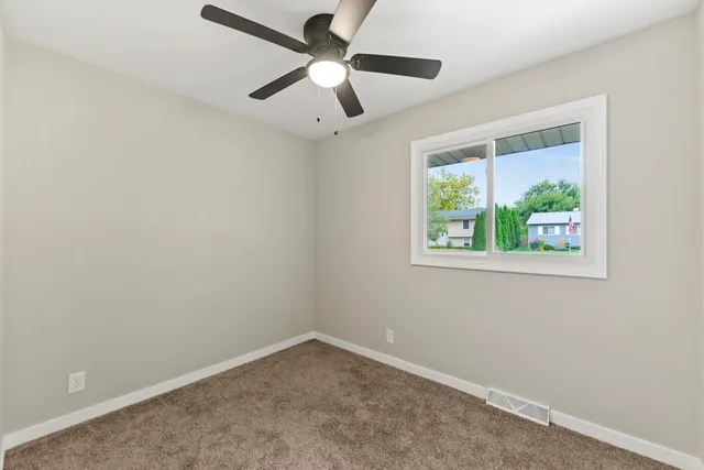 an empty room with a window and a ceiling fan