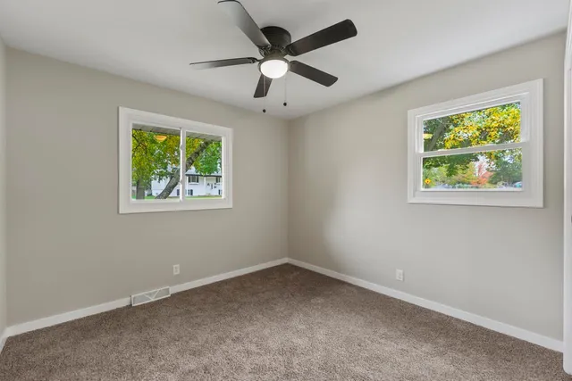 an empty room with windows and ceiling fan