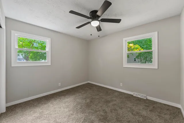 an empty room with windows and ceiling fan