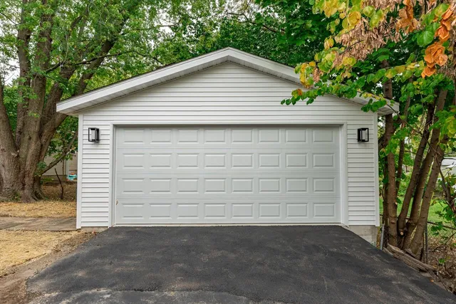 a small white house with a small yard and large tree