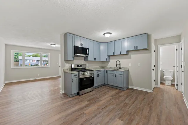 a kitchen with granite countertop a refrigerator stove top oven and sink
