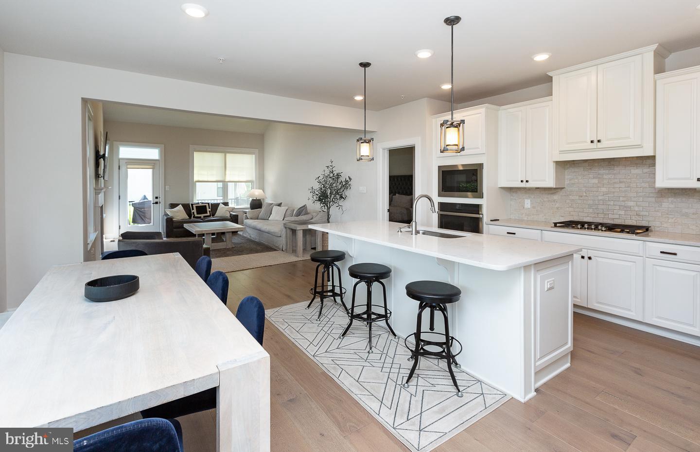 21 The Lane Wayne, PA 19087 - Photo 8 of 57 a kitchen with stainless steel appliances kitchen island granite countertop a stove a sink a dining table and chairs with wooden floor