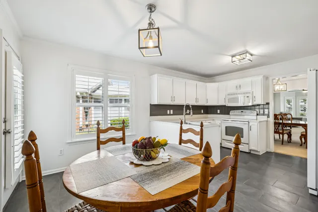 a living room with stainless steel appliances furniture a dining table and a chandelier
