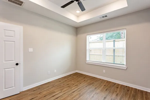 a view of an empty room with wooden floor and a window
