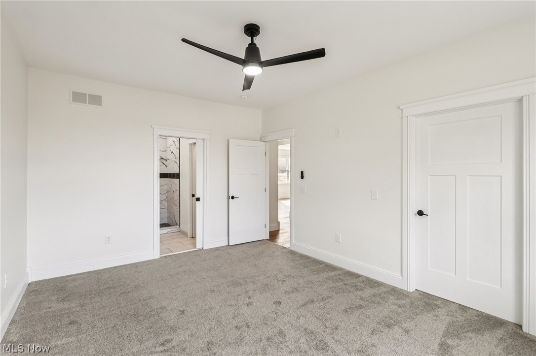6535 North Ridge Road West Geneva, OH 44041 - Photo 18 of 48 Unfurnished bedroom featuring light colored carpet, ensuite bathroom, and ceiling fan