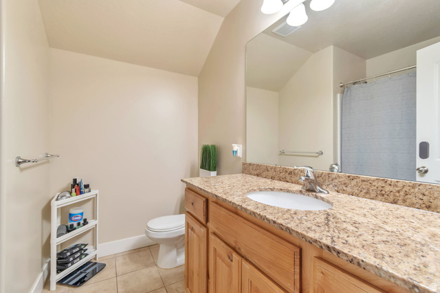 13038 Tower Ridge Drive Riverton, UT 84096 - Photo 27 of 30 Bathroom featuring a single vanity with a granite-style countertop, integrated sink, and wood-finish cabinetry