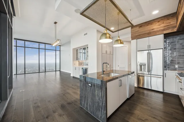 a kitchen with stainless steel appliances granite countertop a refrigerator a sink and white cabinets