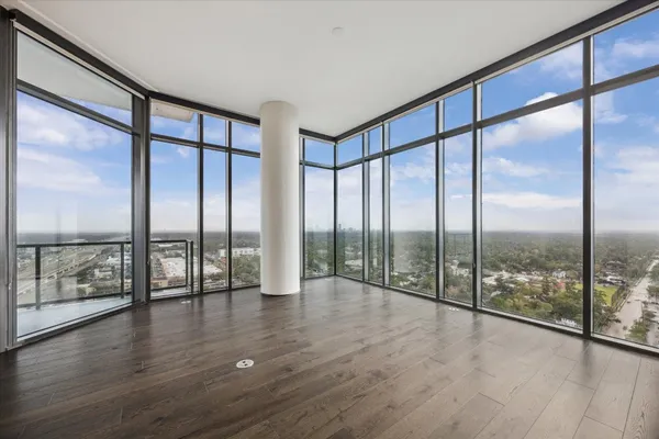 a view of an empty room with wooden floor and windows