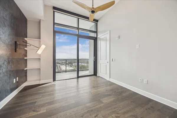 an empty room with wooden floor and a floor to ceiling window