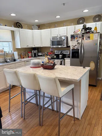 a kitchen with stainless steel appliances kitchen island granite countertop a table chairs and a refrigerator