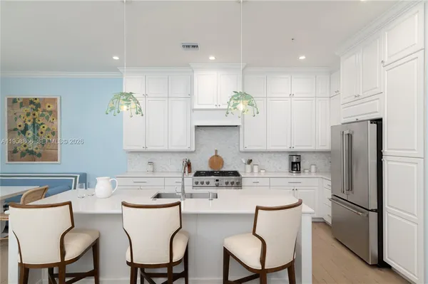 a kitchen with stainless steel appliances a refrigerator a sink a dining table and chairs