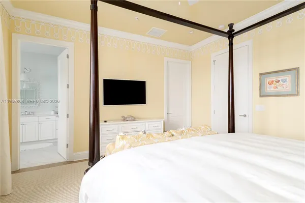 a bedroom with a bed and a flat tv screen on the dresser