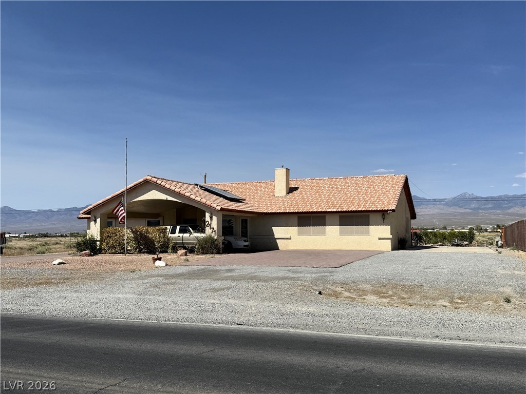 A single-story home with a clay tile roof and a spacious, paved driveway.
