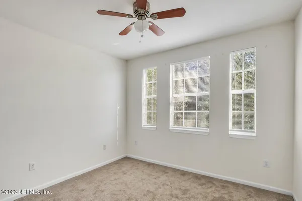 an empty room with windows and fan