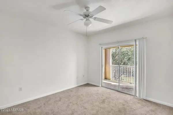 an empty room with a chandelier fan and windows