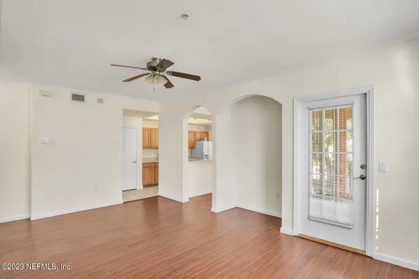 a view of an empty room with chandelier fan and wooden floor