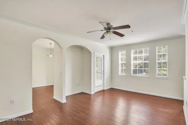 a view of empty room with wooden floor and fan