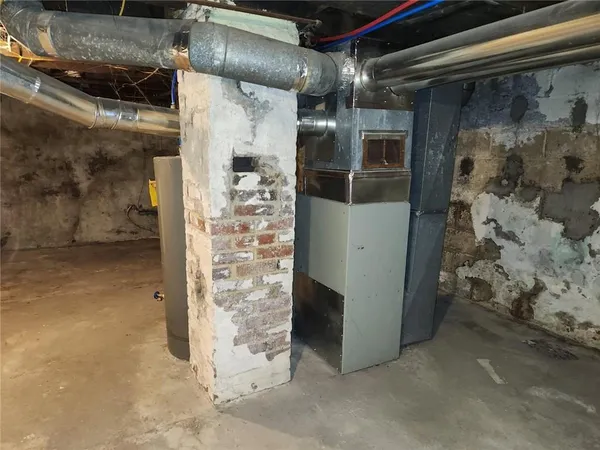 a room with water heater and wooden cabinets