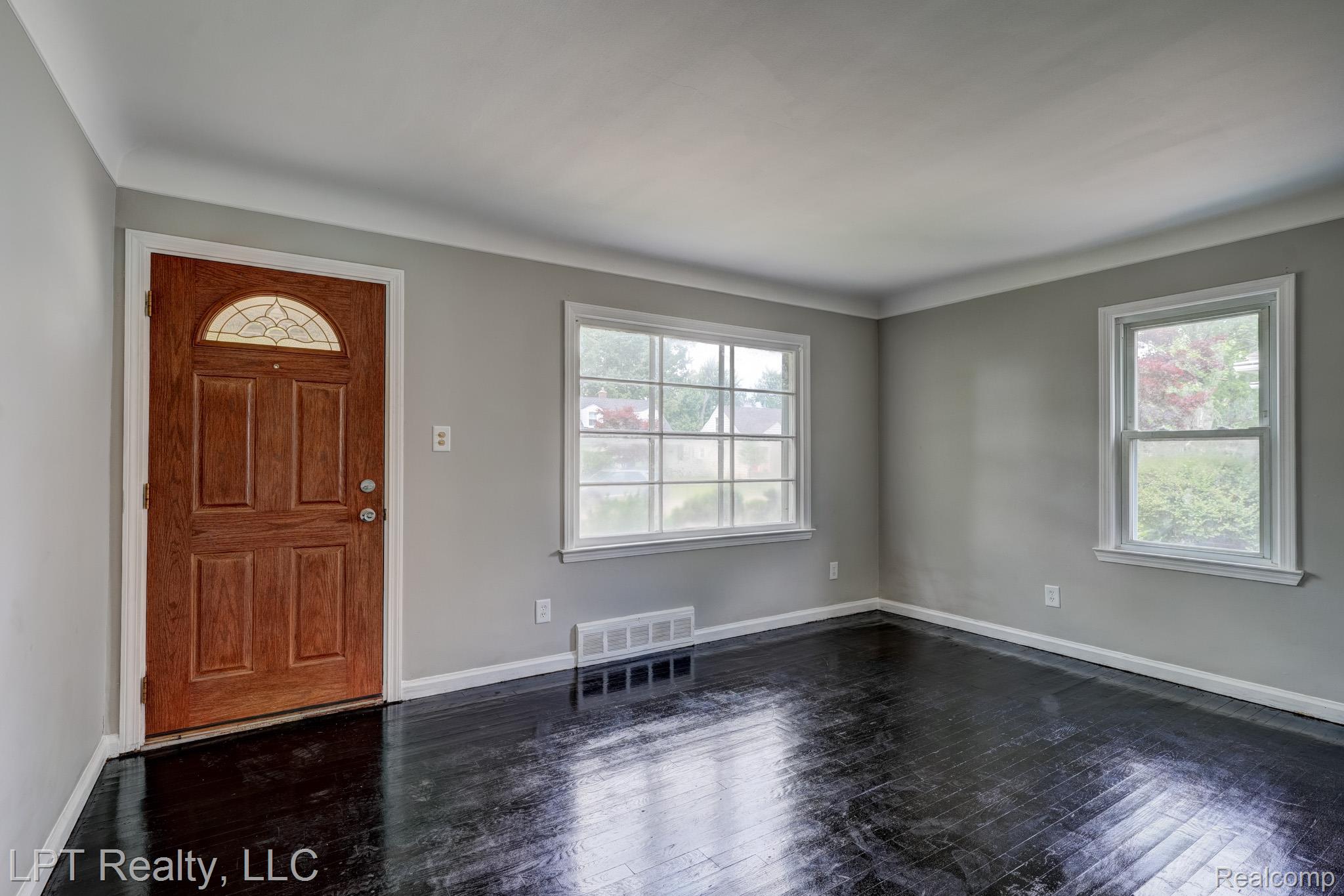 23038 Violet Street Farmington, MI 48336 - Photo 3 of 29 Entryway featuring a paneled wood door with an arched decorative glass insert, dark wood-finish flooring, two windows with white trim, gray wall paint, and white crown molding