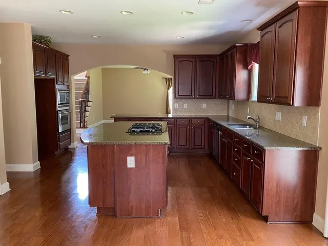 a kitchen with stainless steel appliances granite countertop wooden cabinets a stove a sink and a refrigerator