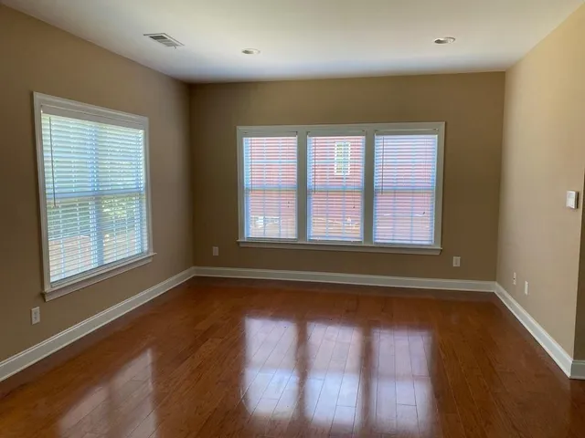 a view of empty room with wooden floor and fan