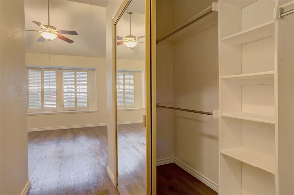 5565 Preston Oaks Road, Unit 120 Dallas, TX 75254 - Photo 9 of 27 Spacious walk-in closet featuring floor-to-ceiling shelving with multiple compartments, mirrored sliding doors with brass hardware, and wood-finish flooring.