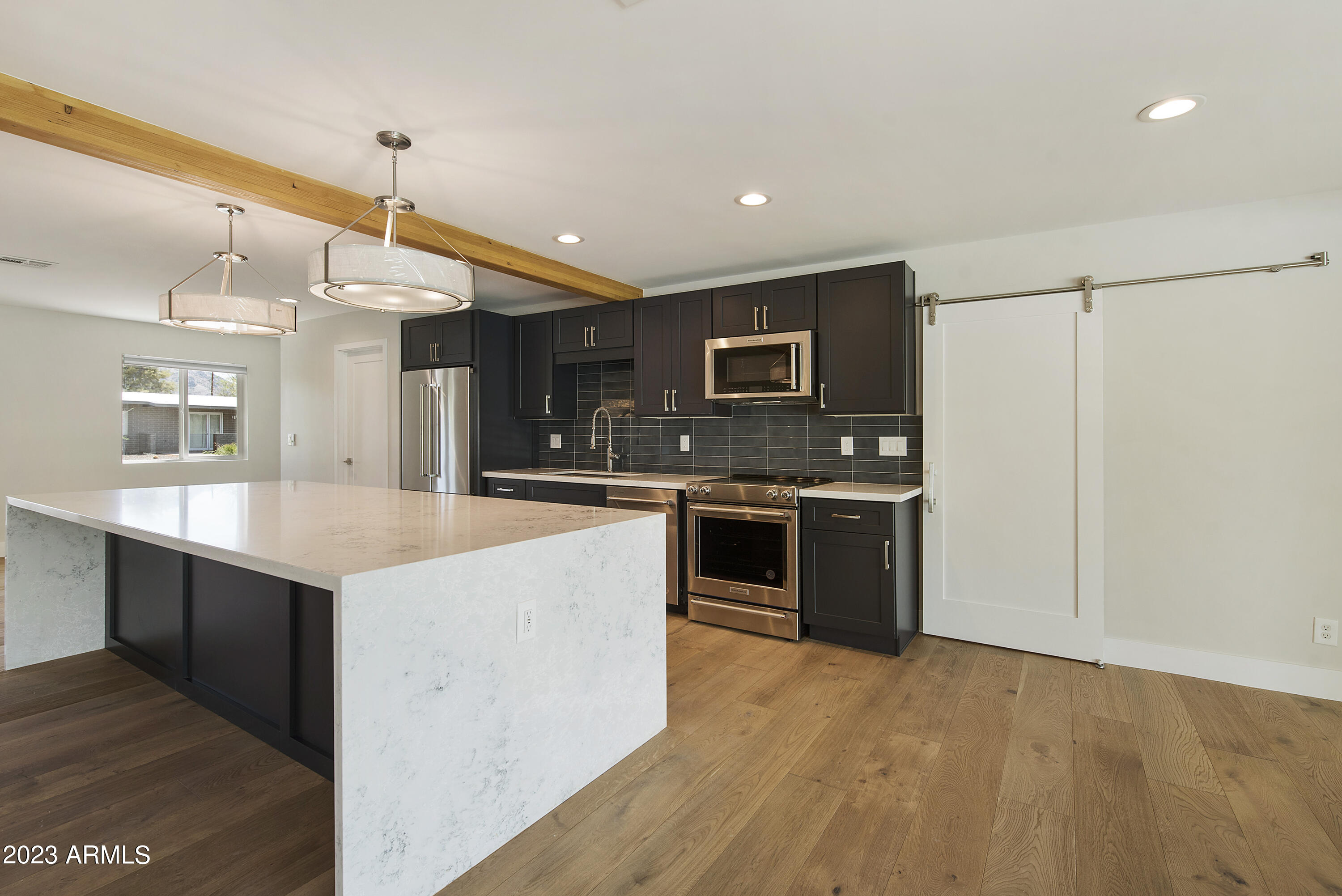 3318 East Onyx Avenue Phoenix, AZ 85028 - Photo 17 of 55 a kitchen with stainless steel appliances a stove top oven a sink dishwasher and a refrigerator with wooden floor