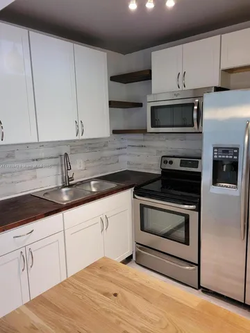 a kitchen with granite countertop white cabinets stainless steel appliances and sink
