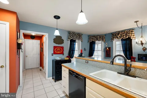a kitchen that has a sink stainless steel appliances a counter space and a view of living room
