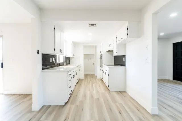 a kitchen with stainless steel appliances a refrigerator sink and white cabinets