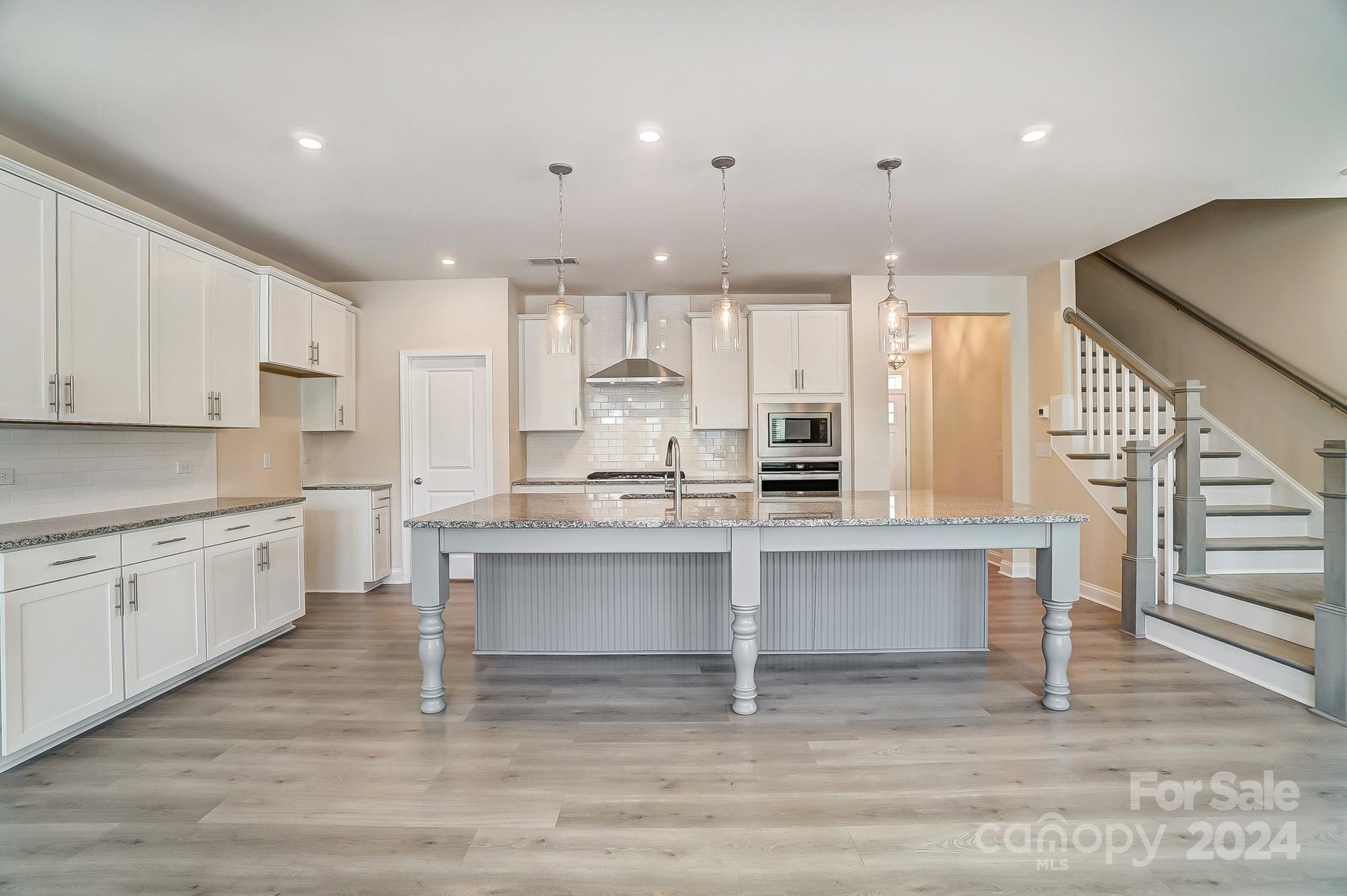 2059 Suttonview Road Fort Mill, SC 29708 - Photo 14 of 44 a open kitchen with kitchen island a sink dishwasher a stove and white cabinets with wooden floor