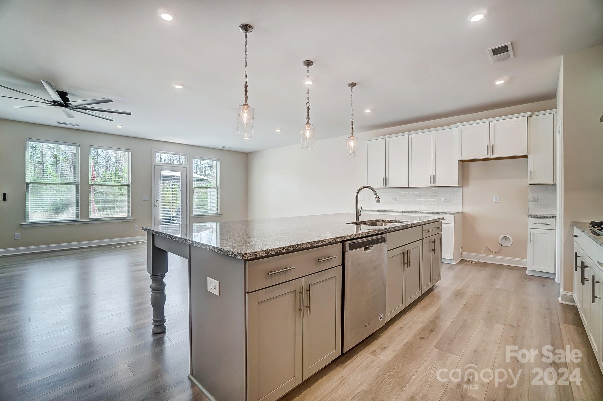 2059 Suttonview Road Fort Mill, SC 29708 - Photo 18 of 44 a kitchen with stainless steel appliances granite countertop a stove a sink a refrigerator and white cabinets with wooden floor