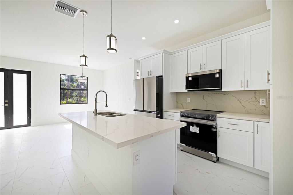 355 Milton Street Port Charlotte, FL 33954 - Photo 15 of 45 a kitchen with stainless steel appliances granite countertop a sink stove and refrigerator