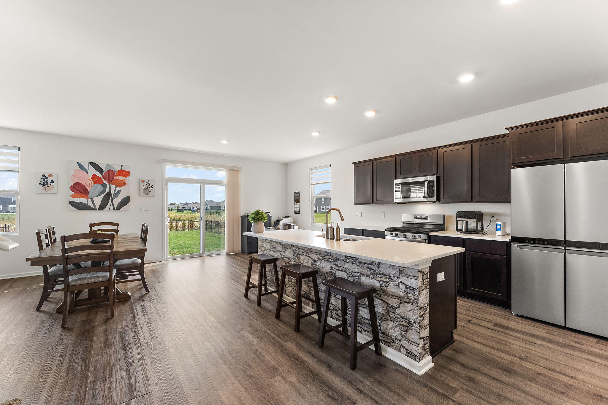 10453 Privet Drive Crown Point, IN 46307 - Photo 8 of 38 a kitchen with stainless steel appliances a dining table chairs stove refrigerator and wooden floor