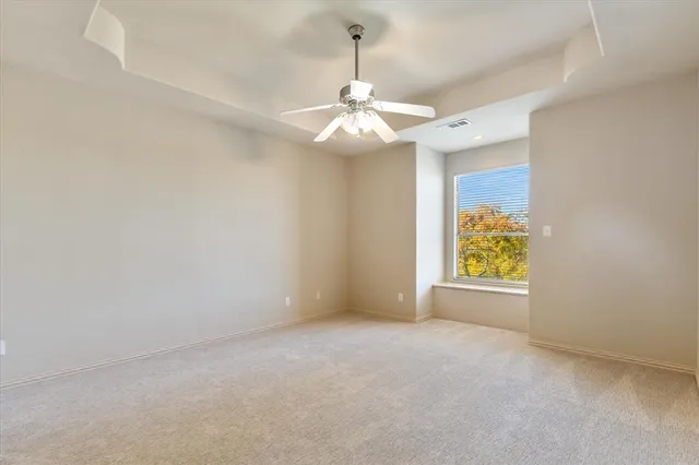 an empty room with windows and ceiling fan