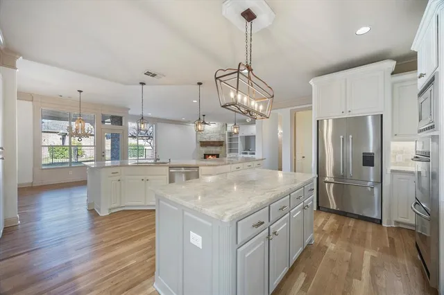 a kitchen with a center island wooden floor stainless steel appliances and windows