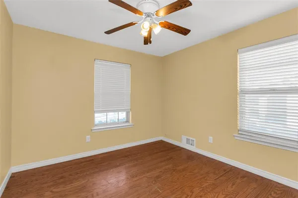 a view of an empty room with window and wooden floor