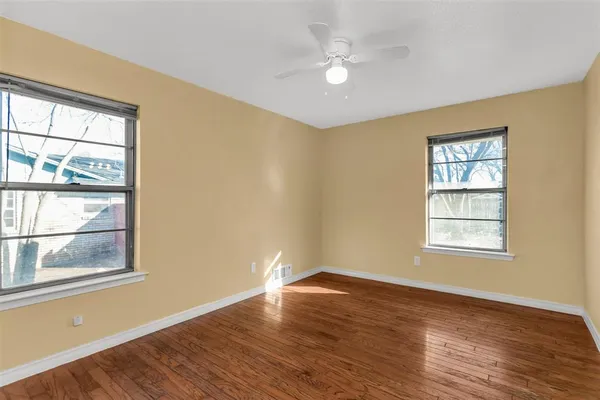 a view of an empty room with wooden floor and window