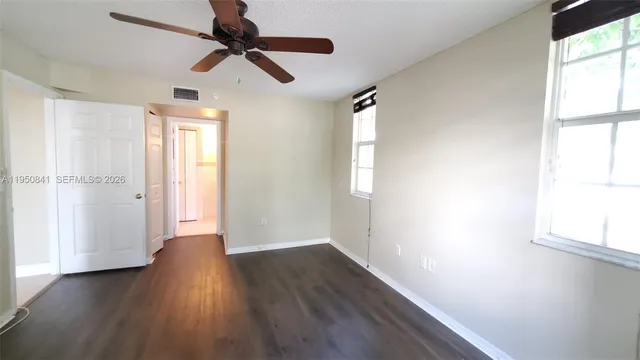 a view of empty room with wooden floor and fan