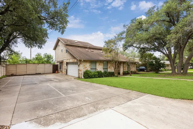 a view of a house with a yard and large tree