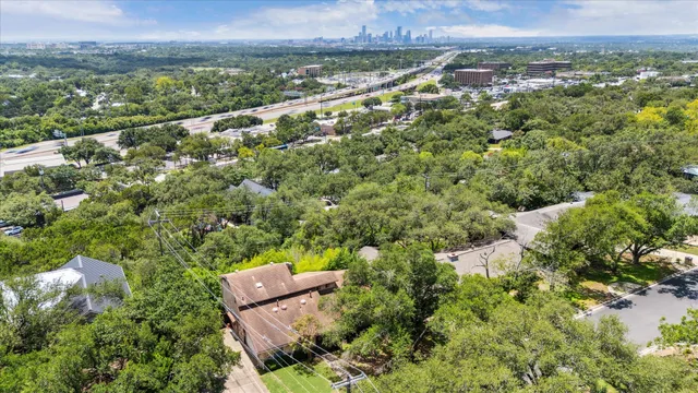 an aerial view of a residential houses with outdoor space and trees