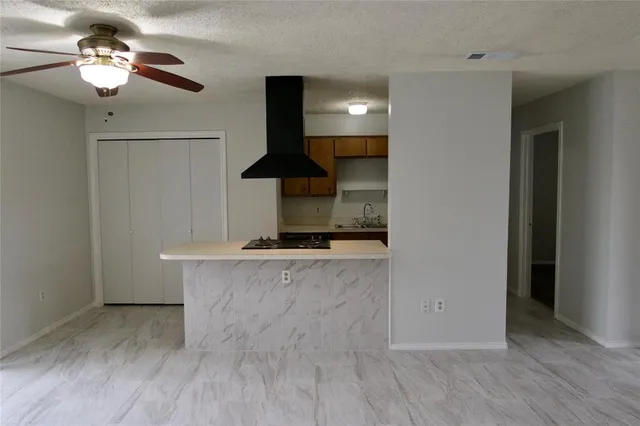 a view of a kitchen with a stove a ceiling fan and wooden floor